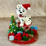 This is a cupcake with a Dalmatian on top of it. The cupcake is a on a cake board decorated for Christmas.